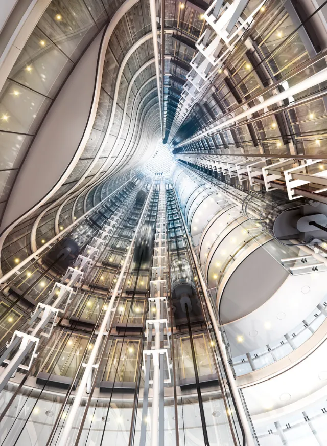 Interior view looking up a high-rise elevator shaft with lights by Eberhard Reimann