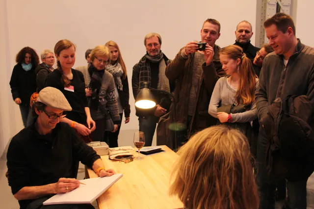 Author Björn von Schlippe signing books as fans watch and photograph