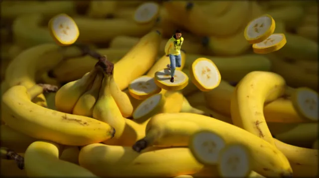 Miniature person standing on sliced bananas surrounded by whole bananas by RIVE GAUCHE