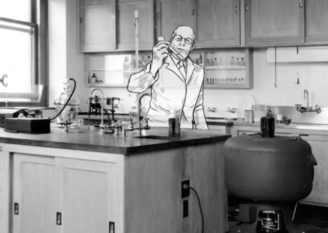 Scientist in white coat holding test tube in laboratory by Björn von Schlippe