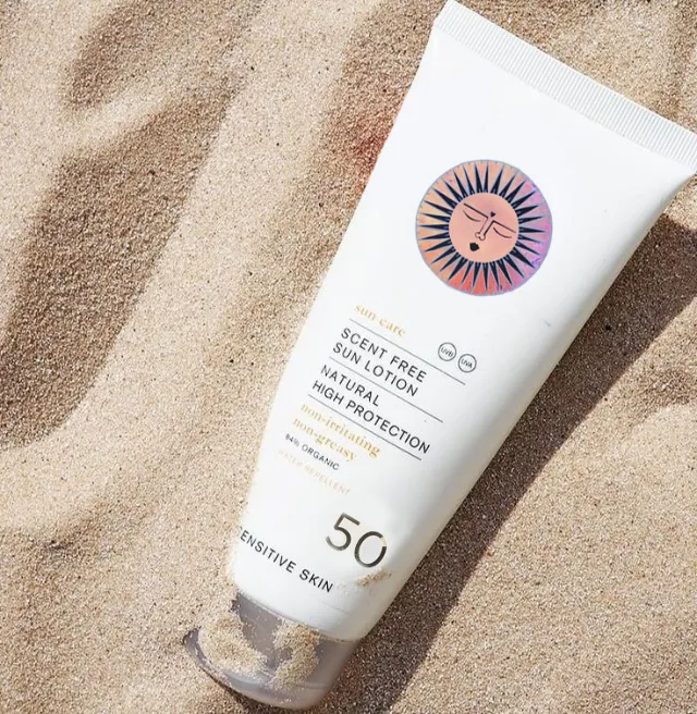 Sunscreen tube labeled SPF 50 on sand by Hannah Davies