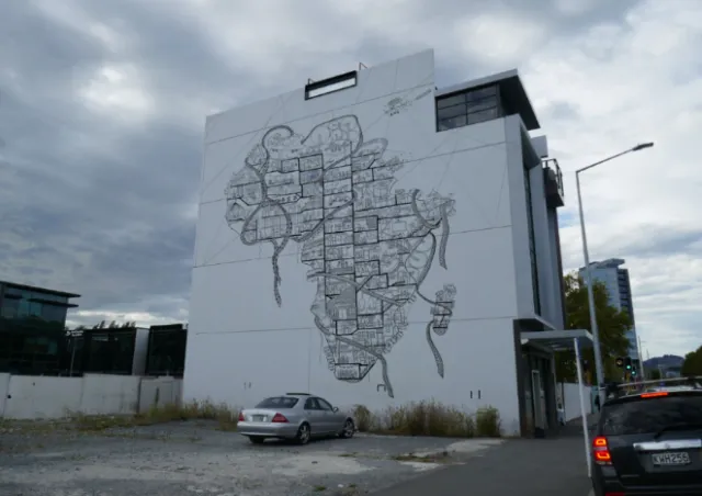 Large mural map on building wall by Ellie Compton with cars in foreground