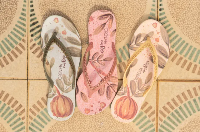 Three flip flops with printed designs on patterned tiled floor by Tai