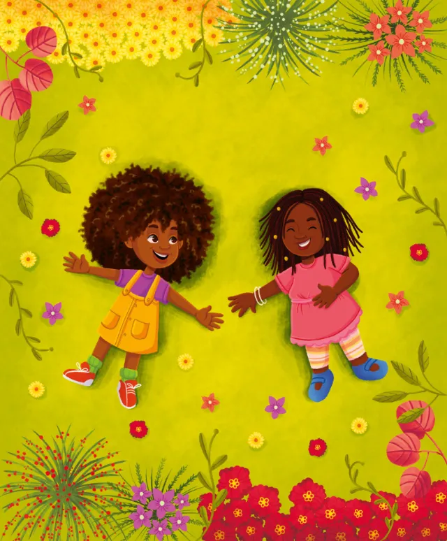 Two happy children lying on green grass with flowers around