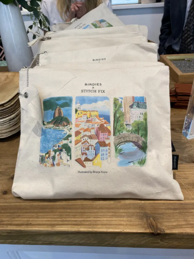Tote bag with three colorful landscape illustrations on display
