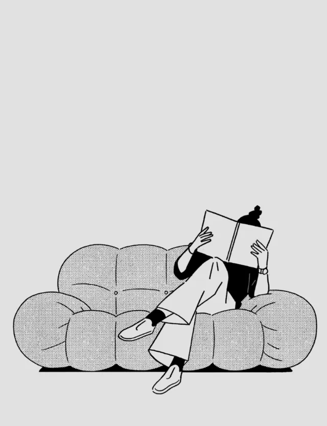 Individual sitting on sofa reading a book