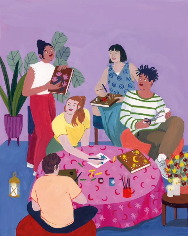 Four people reading and writing around a pink table with plants and lantern