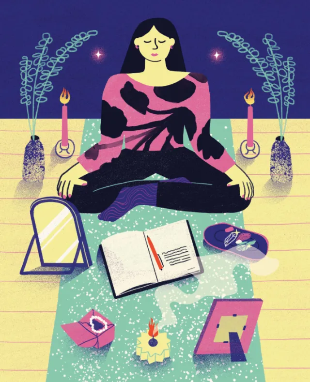 Woman meditating surrounded by candles, incense, open journal, and mirror.