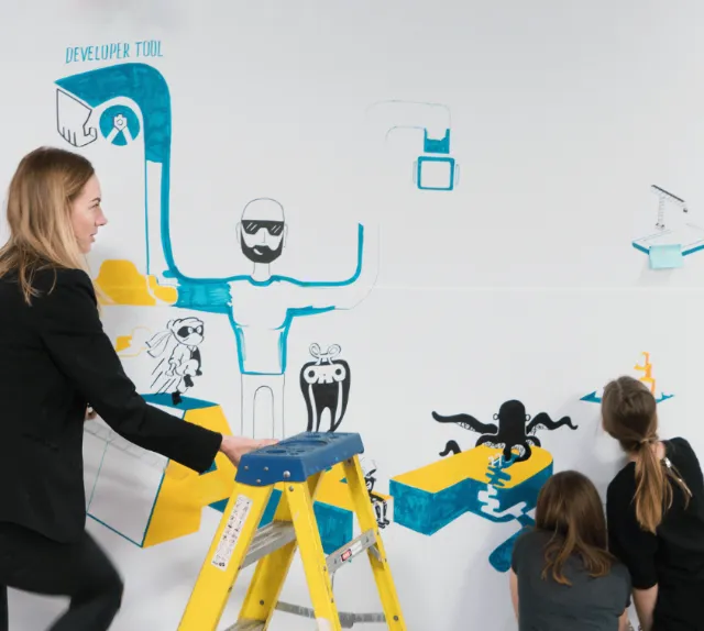 Adults and children painting creative wall mural with blue and black characters