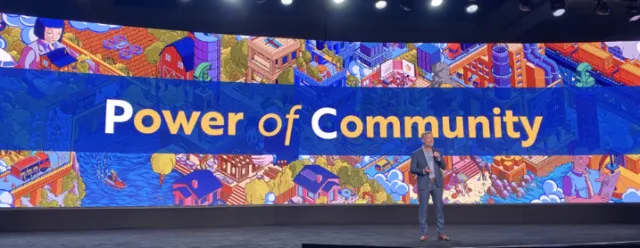 Person speaking on stage with Power of Community banner behind