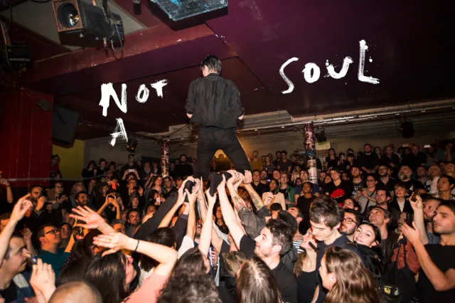 Man standing on crowd's hands at lively concert