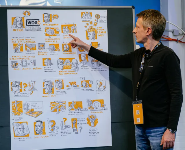 Man presenting illustrated poster with diagrams and text on a board