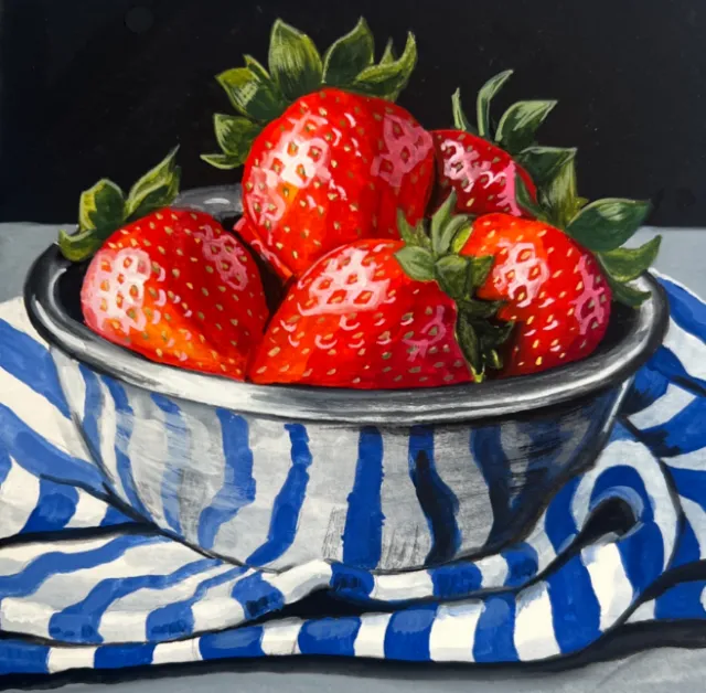Bowl of fresh red strawberries on blue and white striped cloth