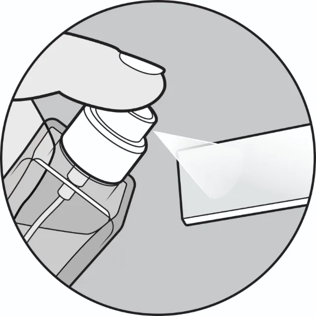 Hand spraying liquid from a spray bottle onto a surface