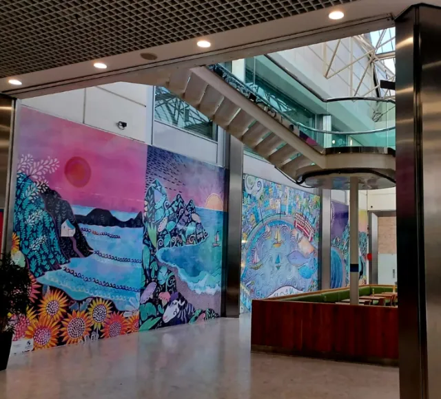 Vibrant mural paintings on walls inside modern building with stairs and seating