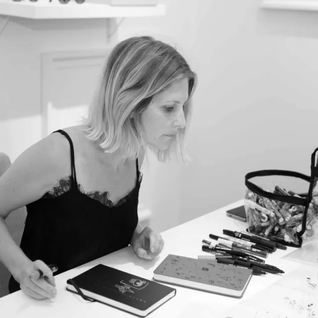 Woman focused on drawing with pens and sketchbook on desk