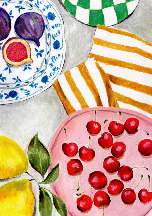 Red cherries on a pink plate with figs and lemons nearby