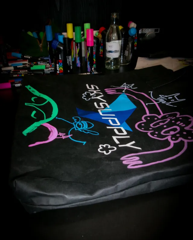 Black fabric decorated with colorful neon graffiti drawings and markers