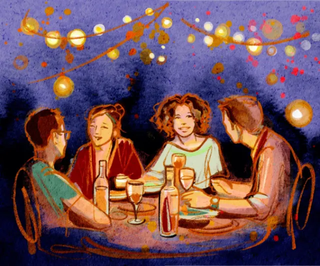 Four people enjoying a summer dinner party under string lights