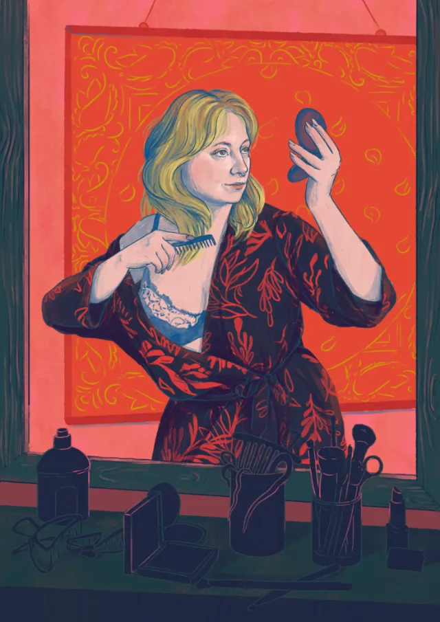 Woman combing her hair while looking in a handheld mirror