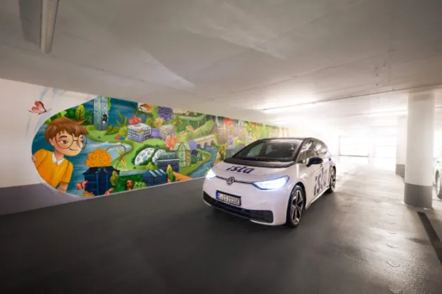 Electric car in underground parking with colorful mural by Alyssa De Asis