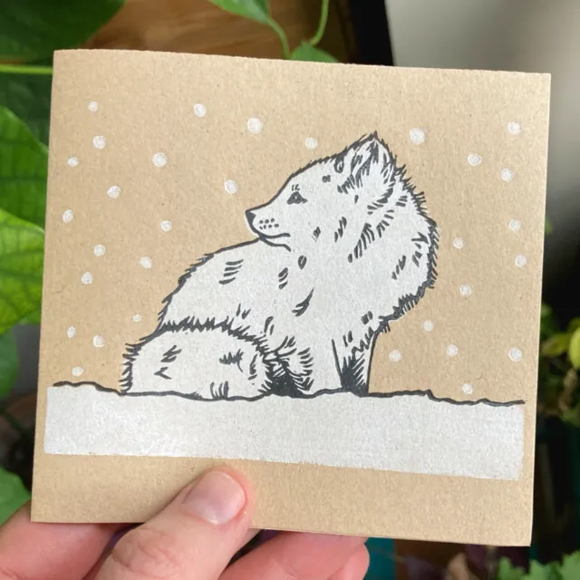 Lino cut of an arctic fox sitting in snow by Emily Robertson