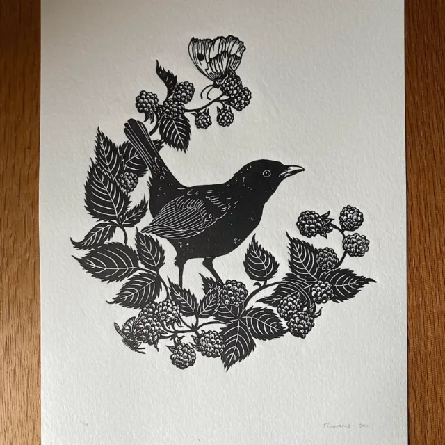 Lino cut of a blackbird perched on blackberry brambles by Emily Robertson
