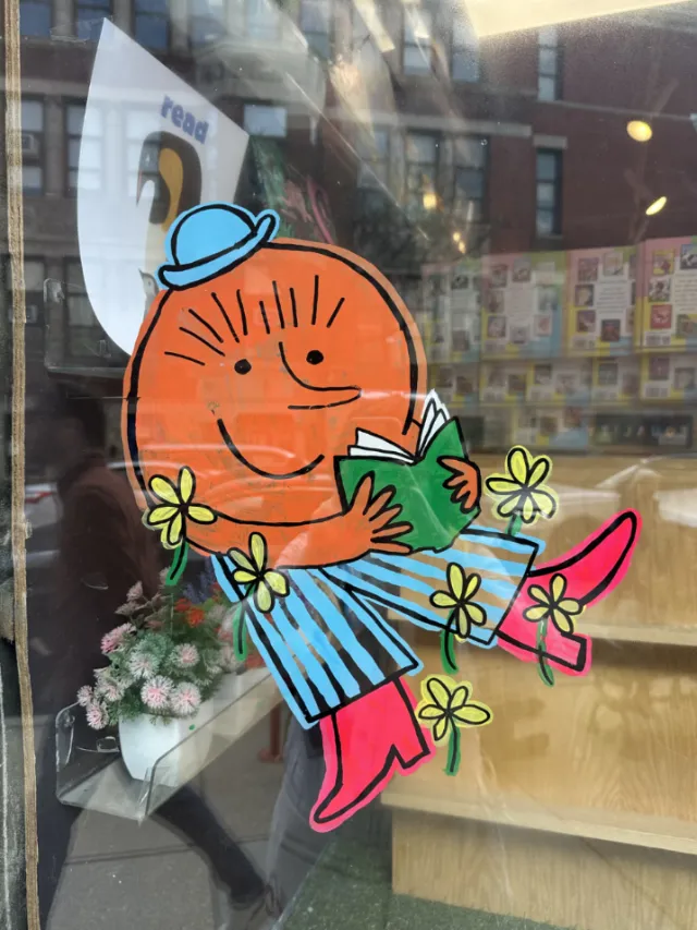 Colorful reading character mural on bookstore window by Ollie Wootton