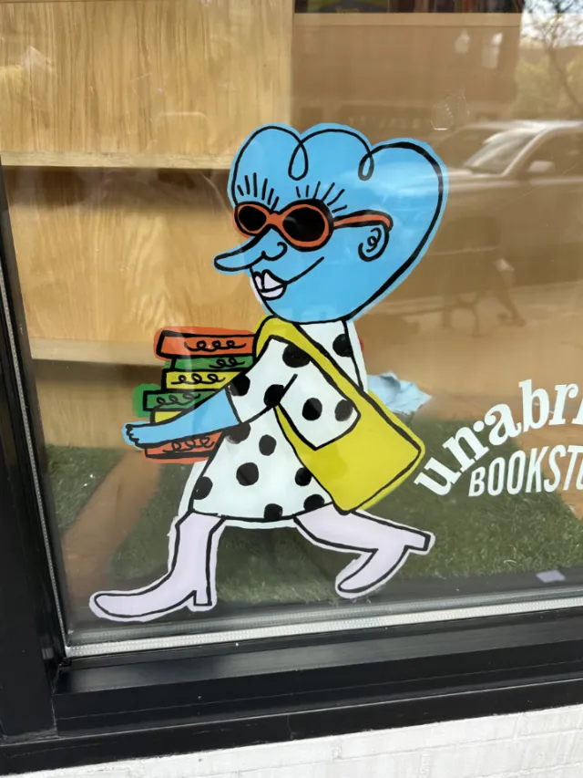 Cartoon woman with blue hair carrying books in Unabridged Books mural by Ollie Wootton