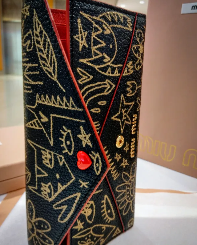 Black clutch with gold abstract designs and red heart button by Nadia Flower