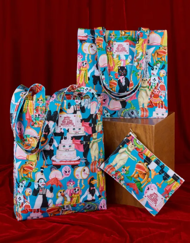 Colorful collage-covered luggage by Juliette Toma displayed against red drapery