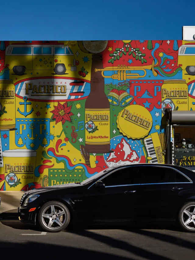 Colorful mural behind a black car, artwork by Season of Victory