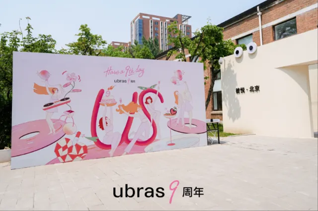 Leah Han’s pink ubras anniversary mural beside a modern brick building.