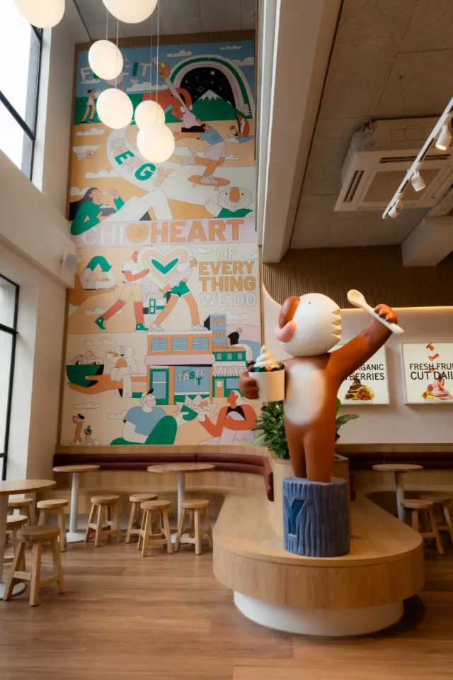 Joseph Carrington mural with a whimsical cat sculpture inside a modern cafe