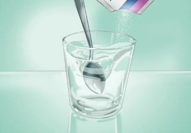 Sugar being poured from a spoon into a clear glass by Björn von Schlippe
