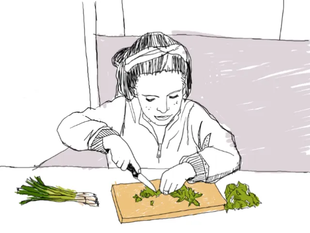 Child with headphones chopping herbs on cutting board by Andreas Schickert