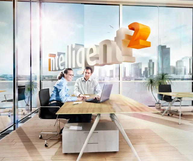 Two professionals working together in a modern office with city views by Tom Krieger