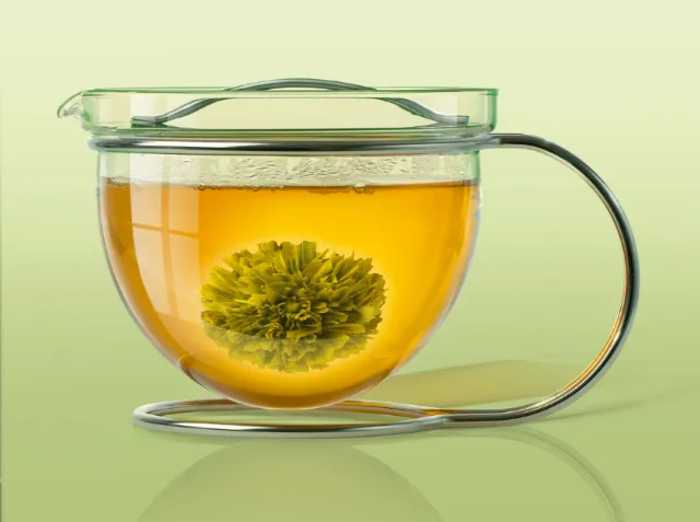 Glass teapot with blooming tea flower in hot water by Tom Krieger
